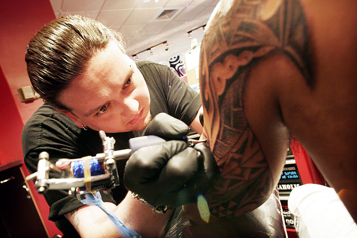 Tattoo artist Jack Omoto, who was raised in Waianae, works on a piece on 